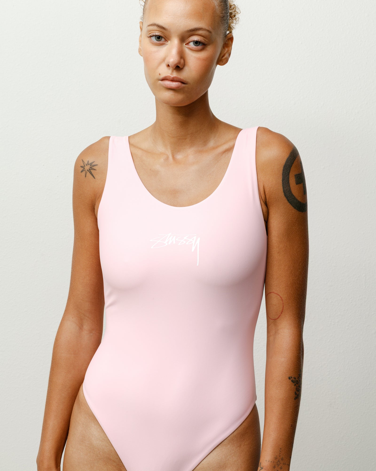 Stüssy 로고가 프린트된 핑크 색상의 서프 스탁 원피스 여성 레귤러 수영복은 스쿠프 넥라인과 신축성 소재가 특징입니다.