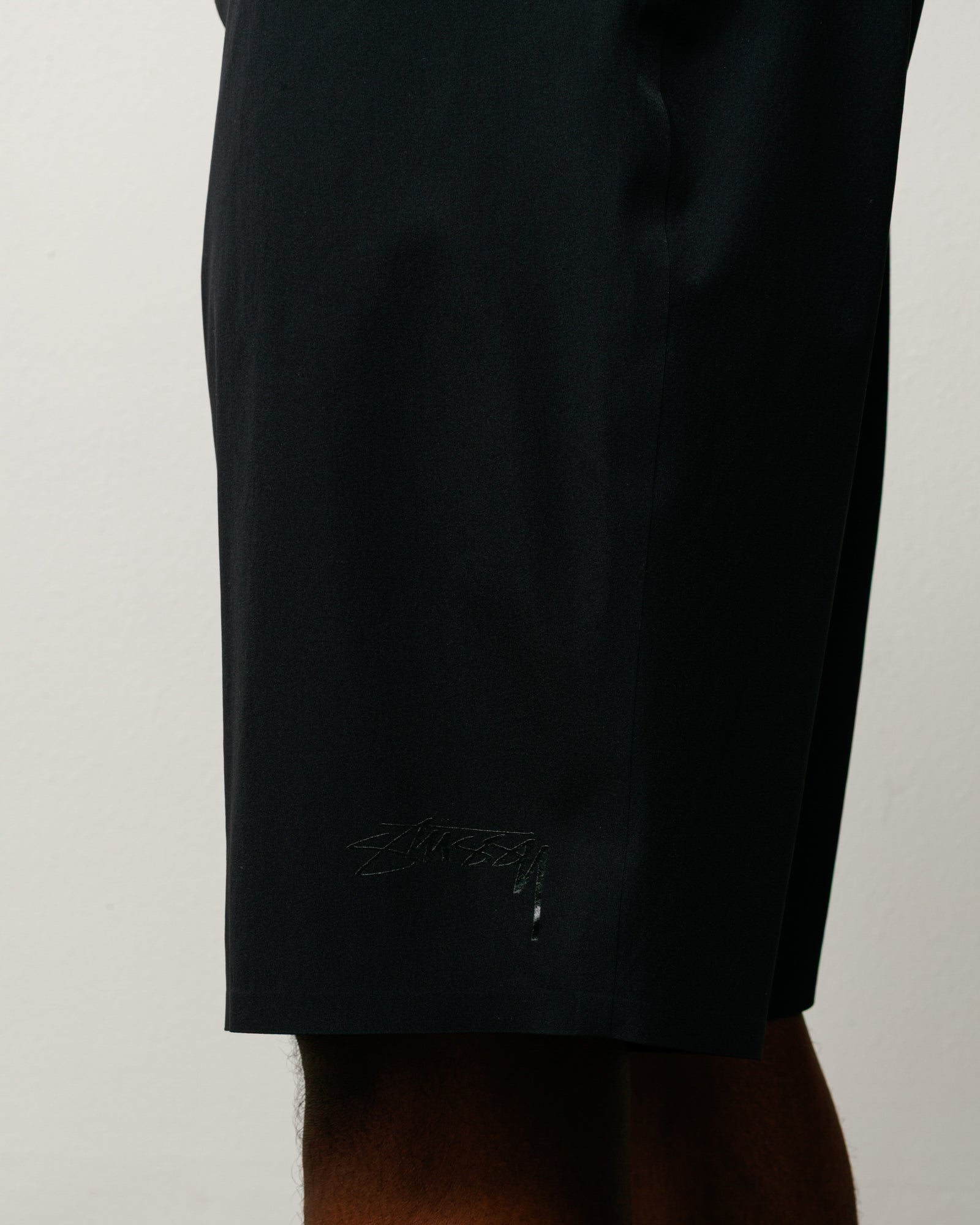 블랙 컬러 스트레치 나일론 소재 보드 쇼츠, 밑단에 톤온톤 Stüssy 로고 프린트 디테일