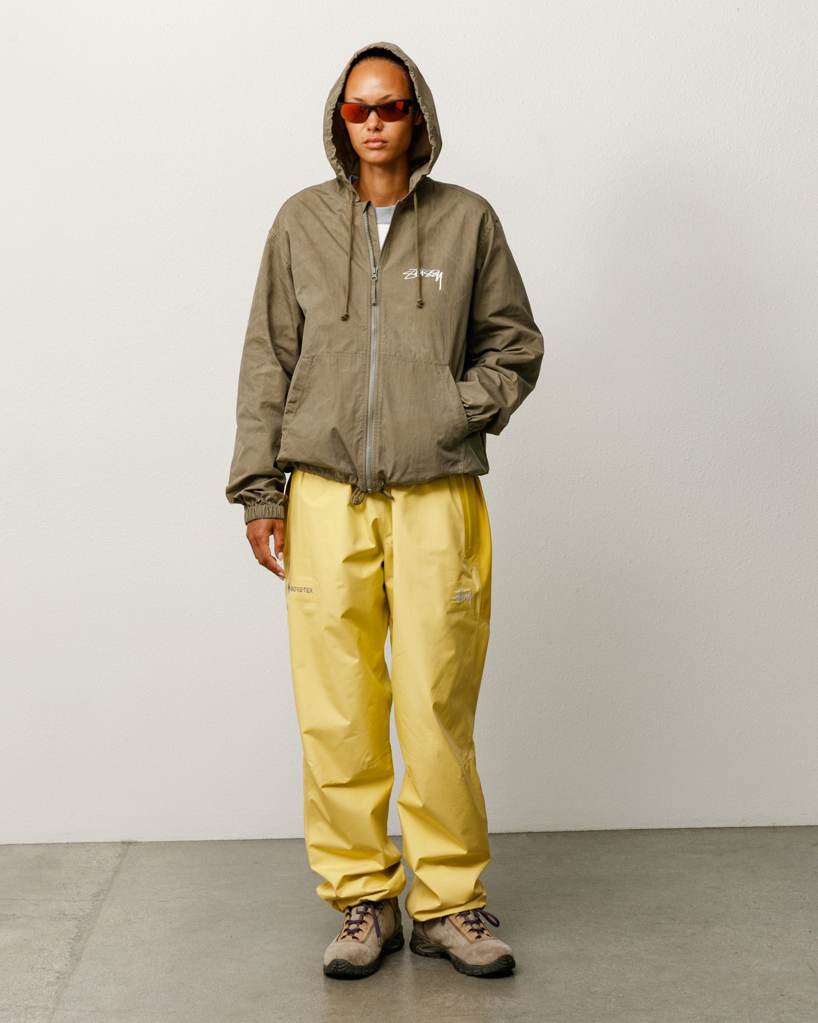 올리브 컬러 Stüssy 왁스드 코튼 비치 셸 재킷, 후드와 가슴 로고, YKK 지퍼 여밈, 릴랙스드 핏