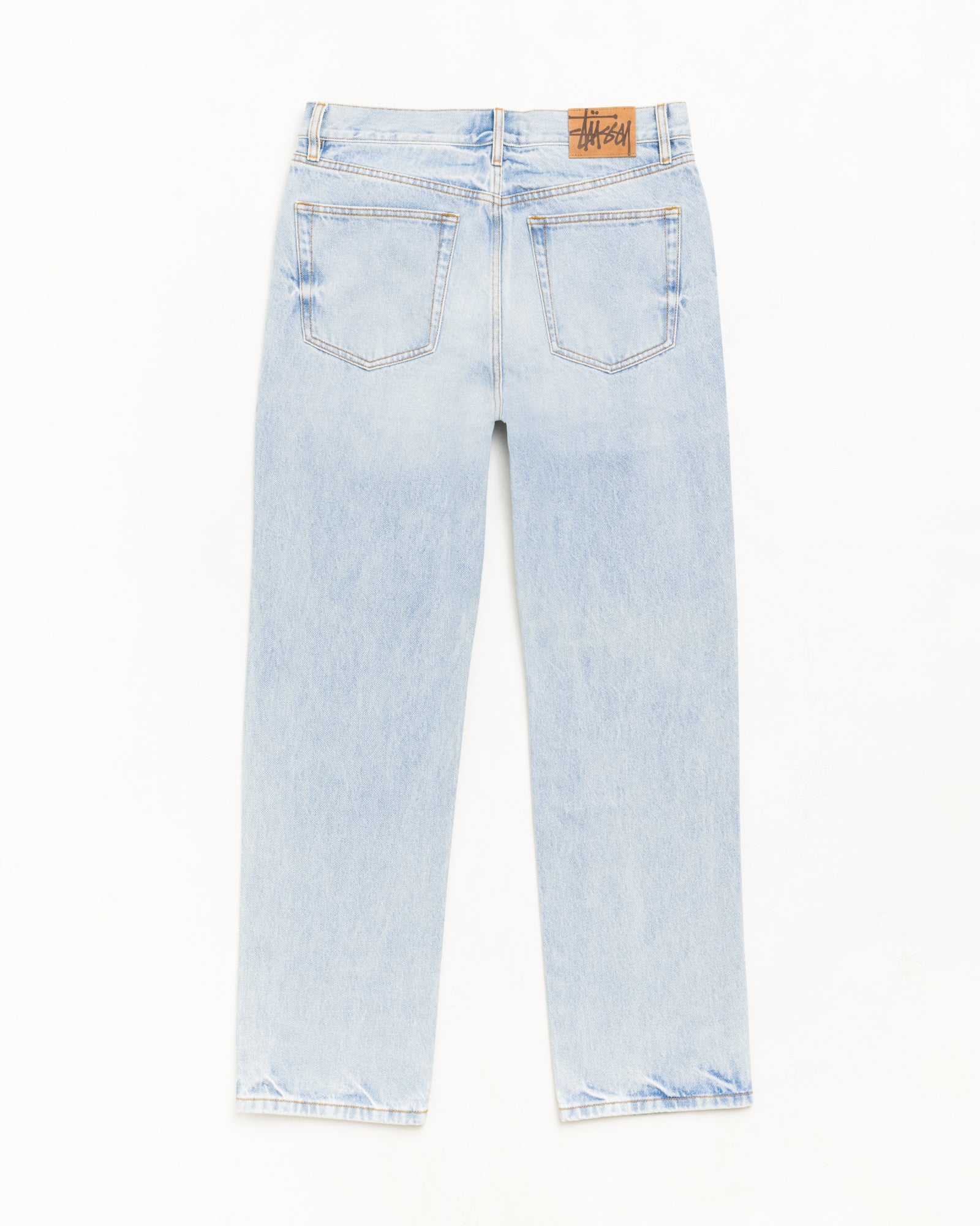 라이트 워시 인디고 슬림 핏 데님 진, 뒷포켓과 스웨이드 Stüssy 로고 패치 디테일.