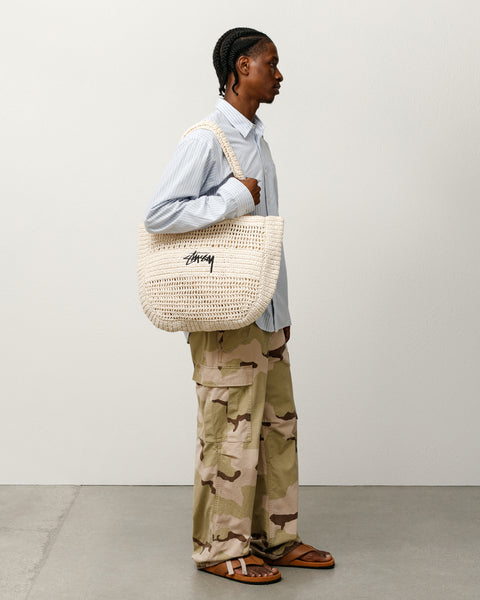 아이보리 컬러의 Stüssy 우븐 토트 백 액세서리는 핸드메이드 라피아 소재와 전면의 로고 자수 디테일이 특징입니다