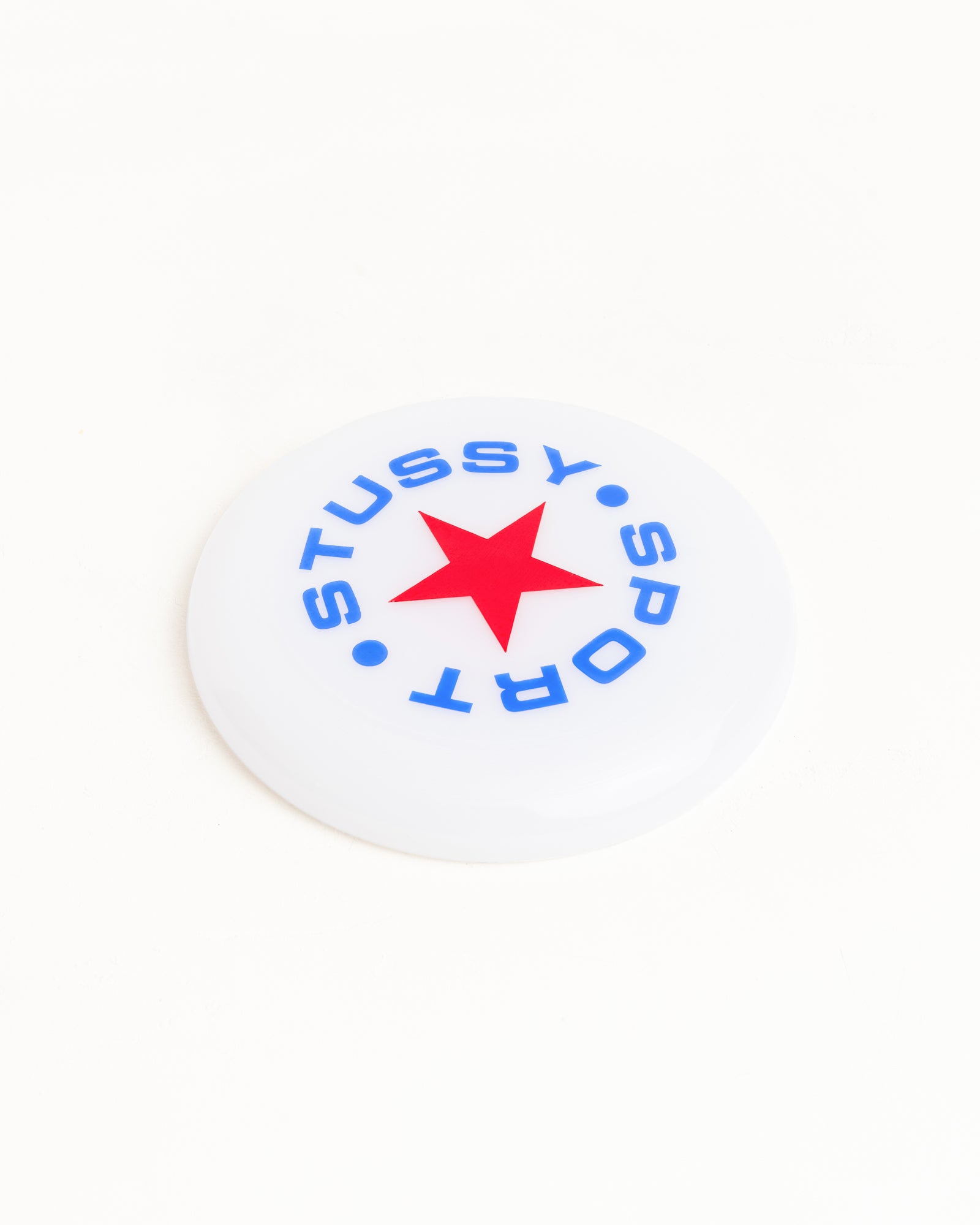 상단에 블루 및 레드 컬러의 로고 아트워크가 프린트된 클리어 색상의 Stüssy Sport Frisbee 액세서리